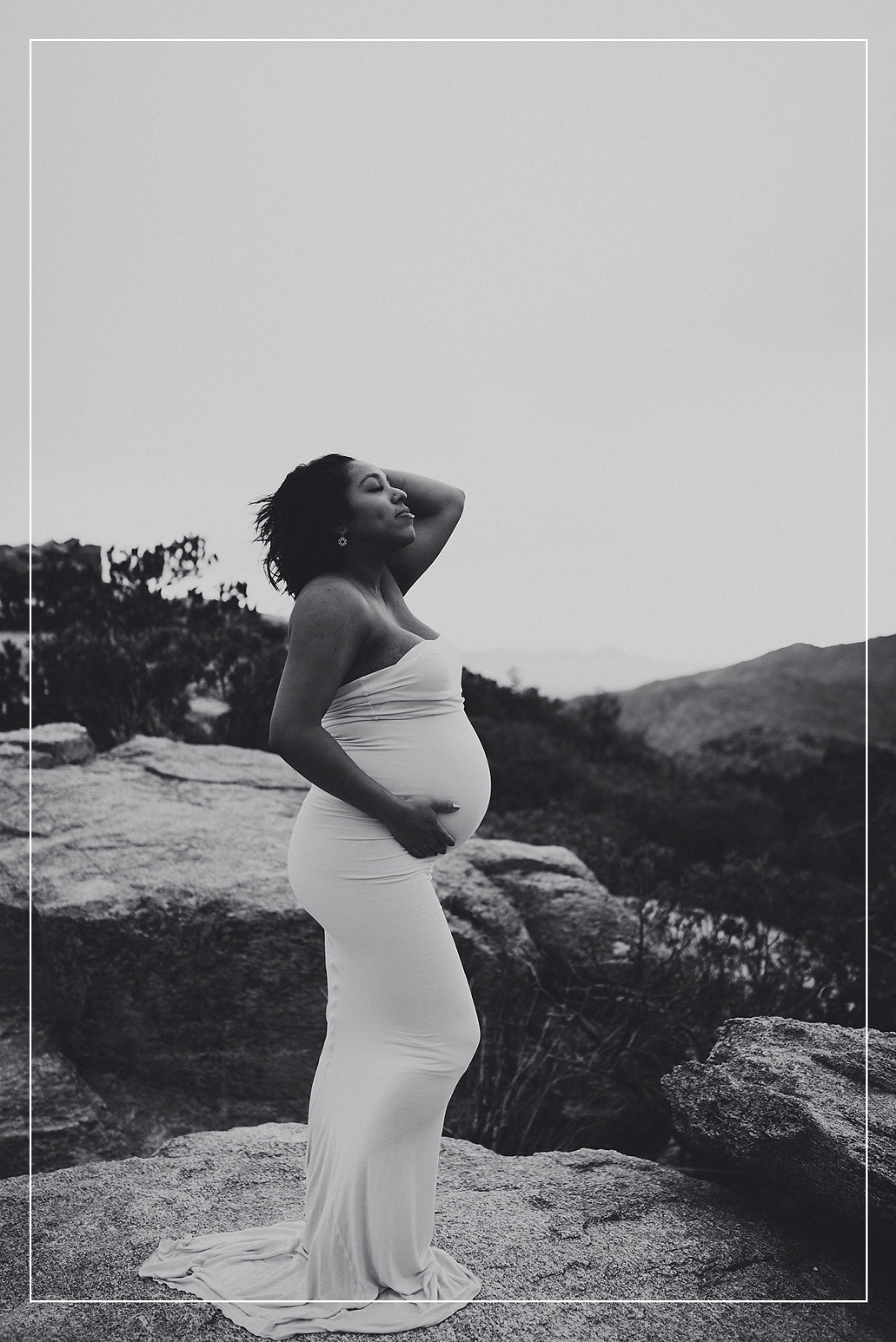Pregnant woman in a white dress, captured in a serene and powerful maternity photo session in Utah, with a breathtaking natural landscape backdrop.