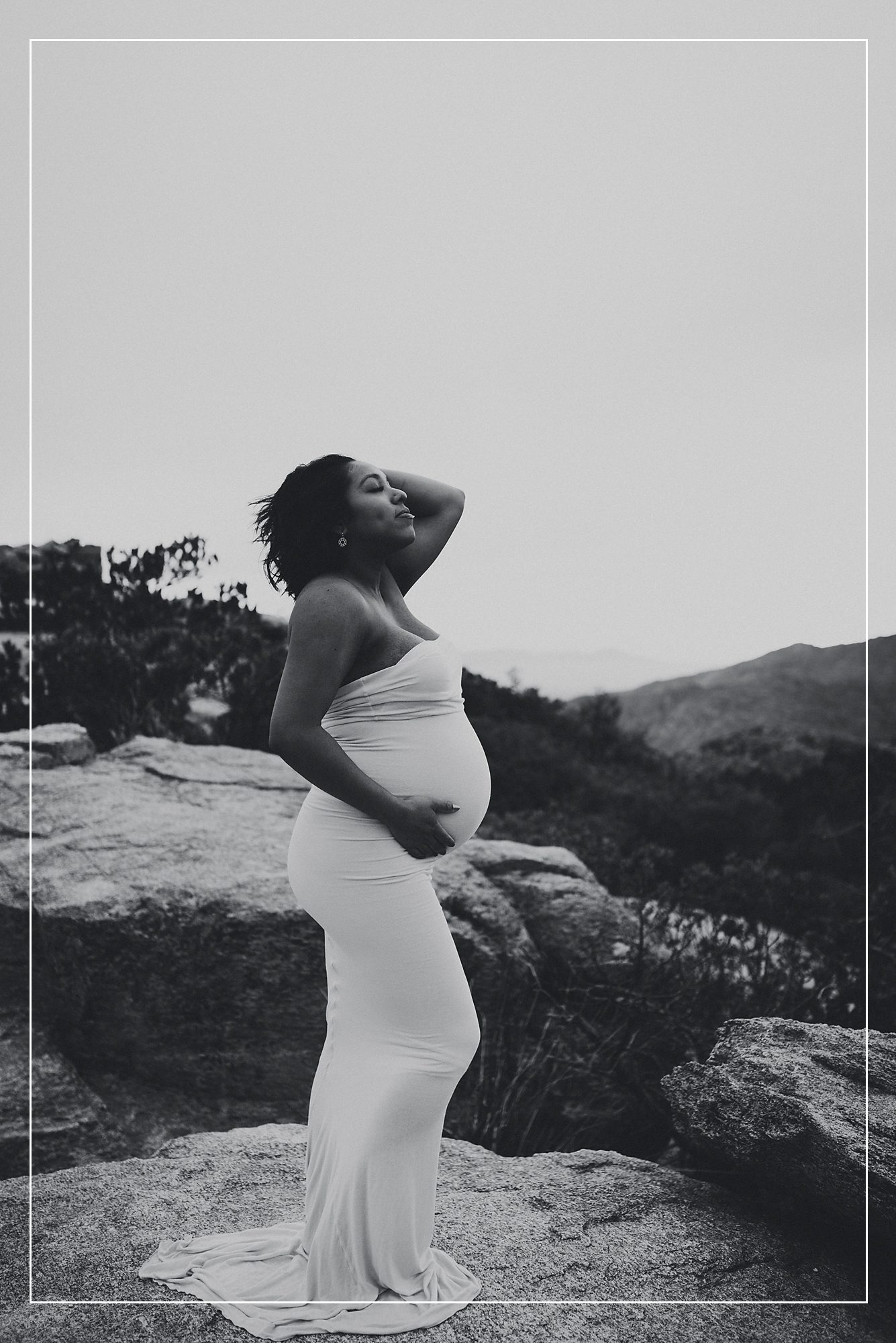 Pregnant woman in a white dress, captured in a serene and powerful maternity photo session in Utah, with a breathtaking natural landscape backdrop.