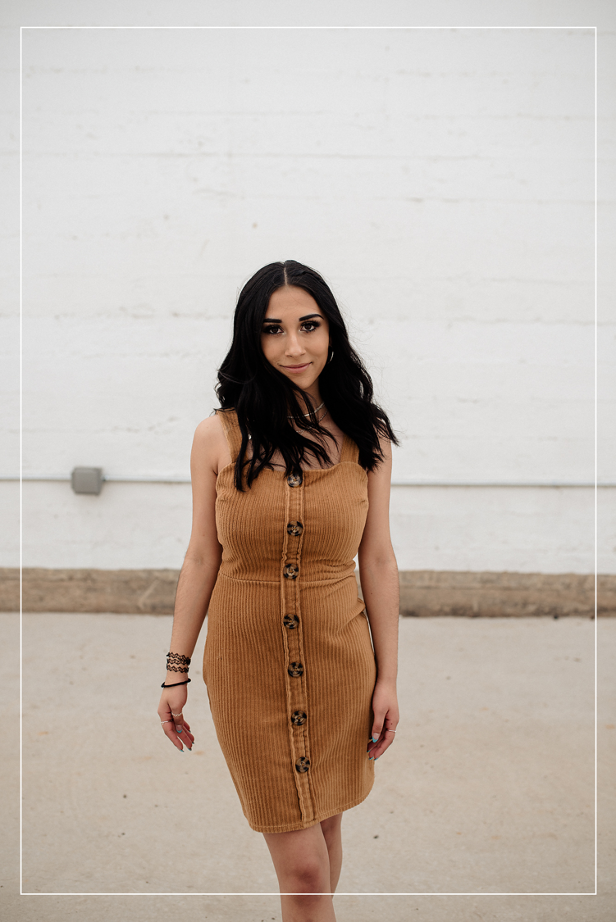 High school senior in a stylish brown ribbed dress, captured in an urban photo session in Utah with a clean, modern background.